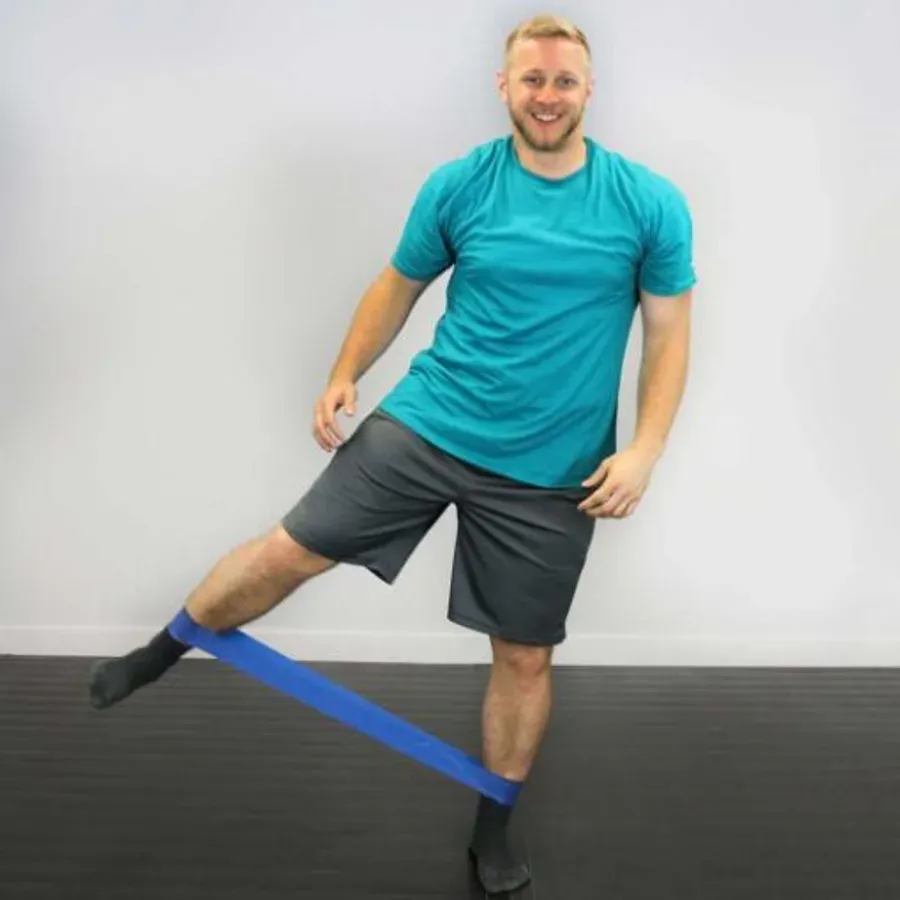 A man stepping one leg out to the side against a blue band loop around both ankles