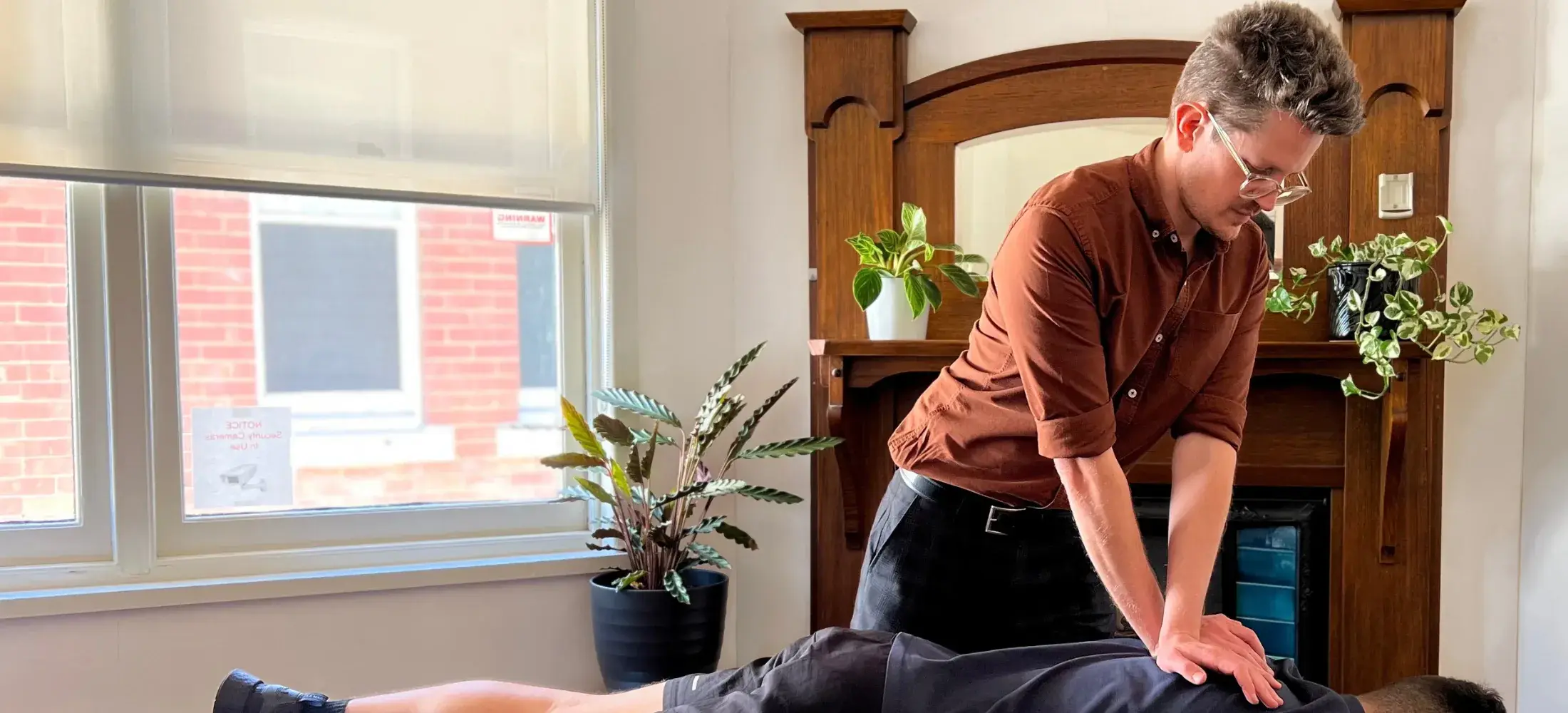 A chiropractor with both hands on a patient's back in a treatment room at the clinic