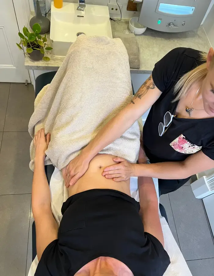 A therapist performing abdominal massage during a colonic irrigation session