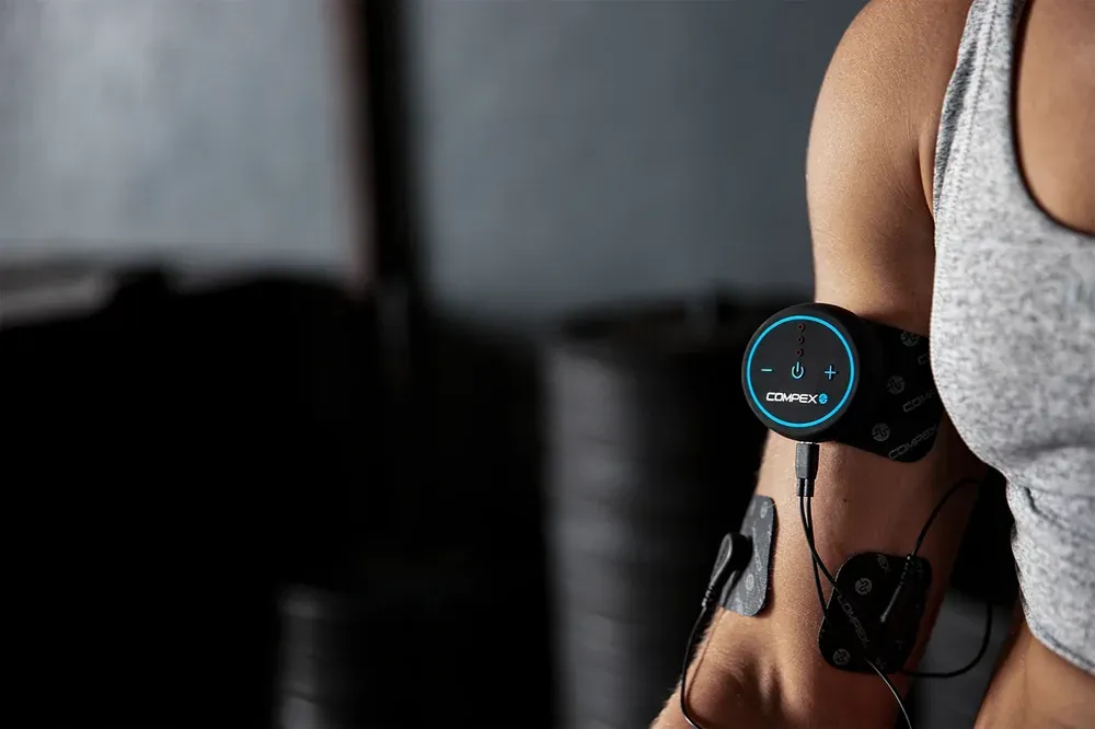 A pod clipped to electrodes on a woman's upper arm at the gym