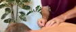 A practitioner placing a fine needle into a patient's shoulder muscle