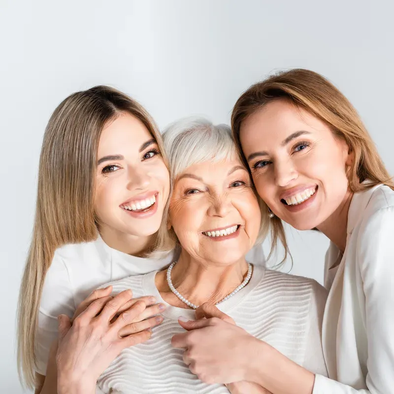 Three generations of women standing close together and smiling