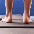 Bare feet standing on a pressure plate, with the scan showing on a tablet beside it