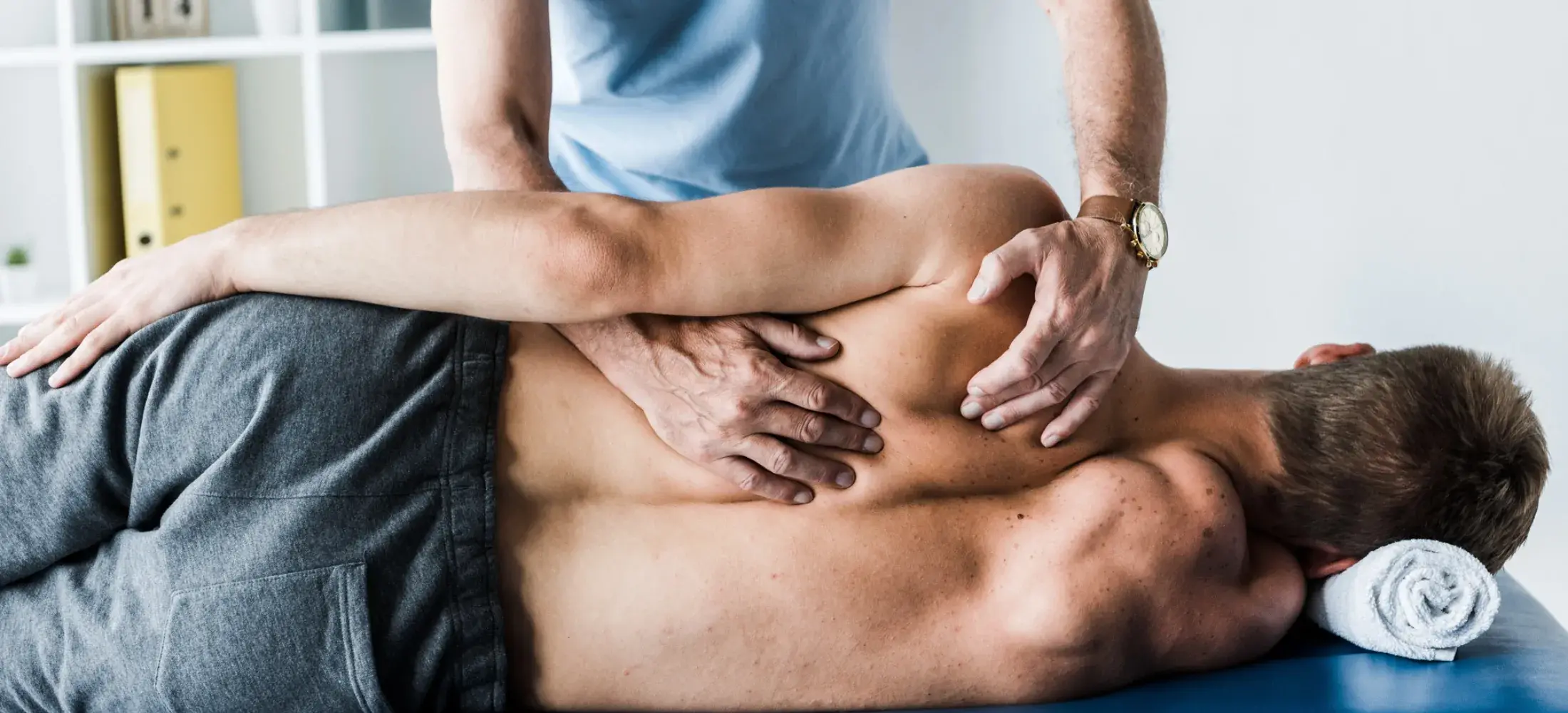 A practitioner's hands working along a patient's back during treatment