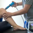 A shockwave therapy handpiece being applied to a patient's knee