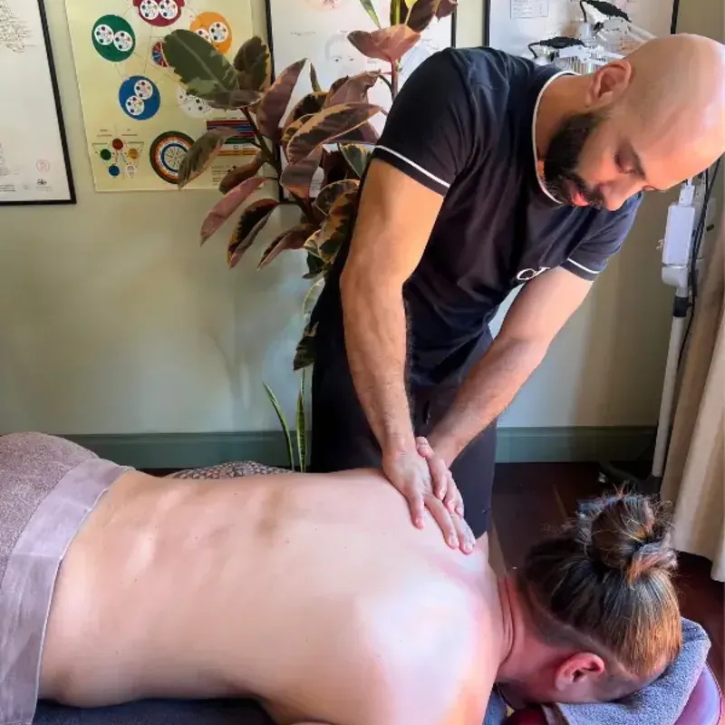 A massage therapist working on a patient's upper back