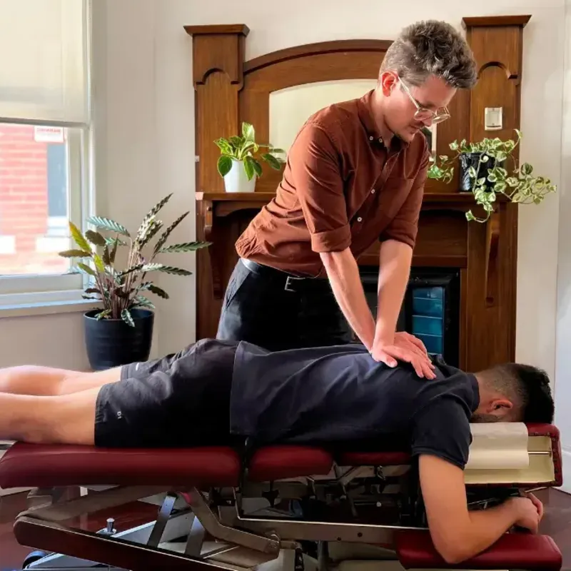 A chiropractor adjusting a patient's mid back on a treatment table