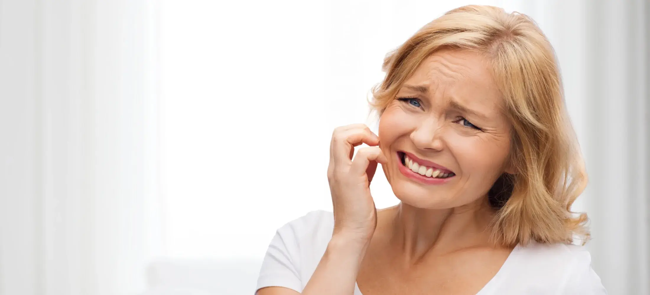 A woman scratching irritated skin on her cheek
