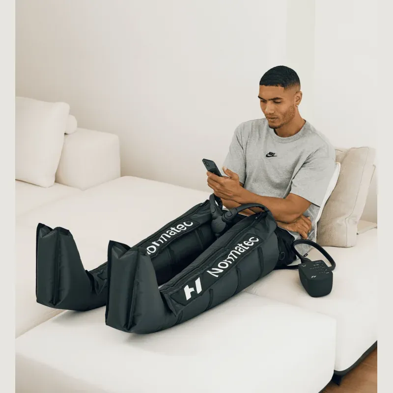 The attachments worn seated on a sofa, showing that they reach from foot to upper thigh