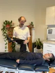 A physiotherapist assessing a seated patient's knee