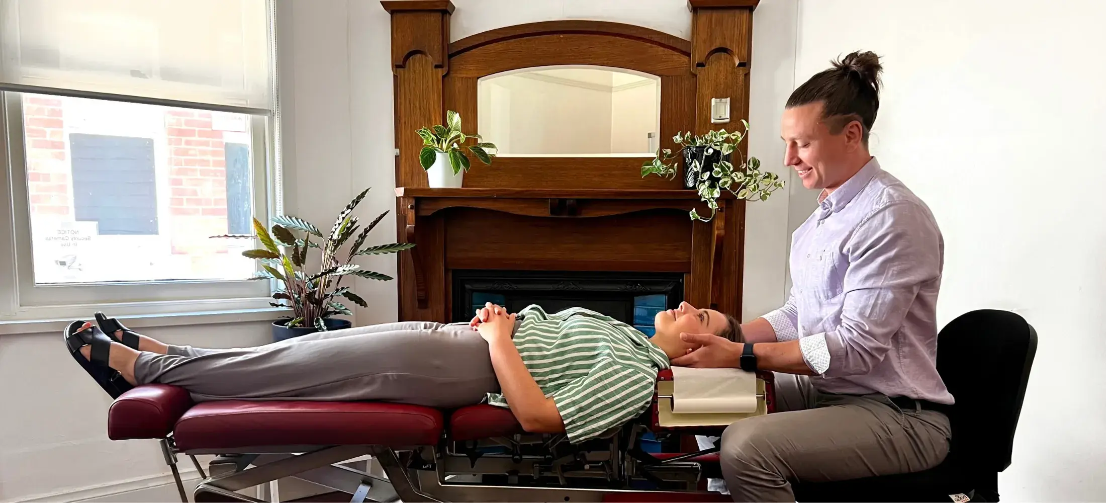 A practitioner supporting a patient's neck on a treatment table in the clinic's front room