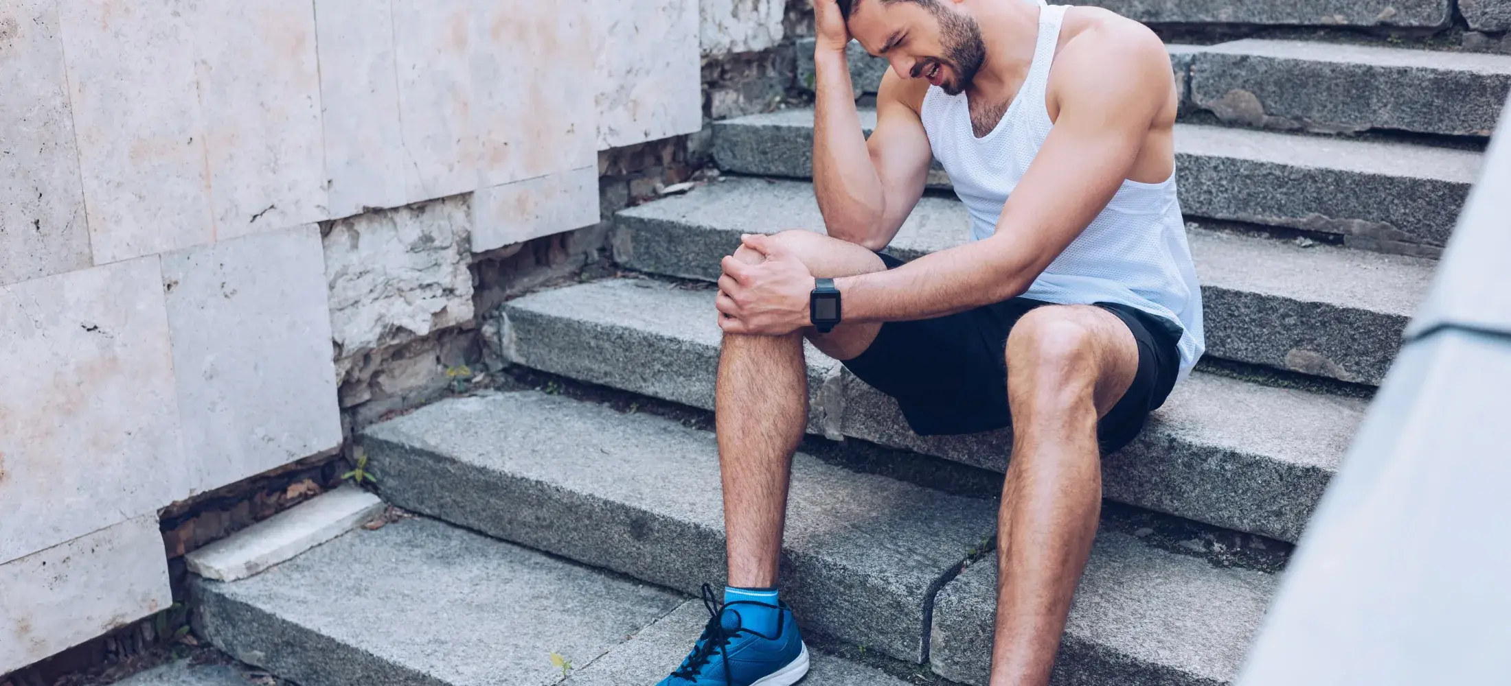 A runner sitting on stone steps holding the front of one knee