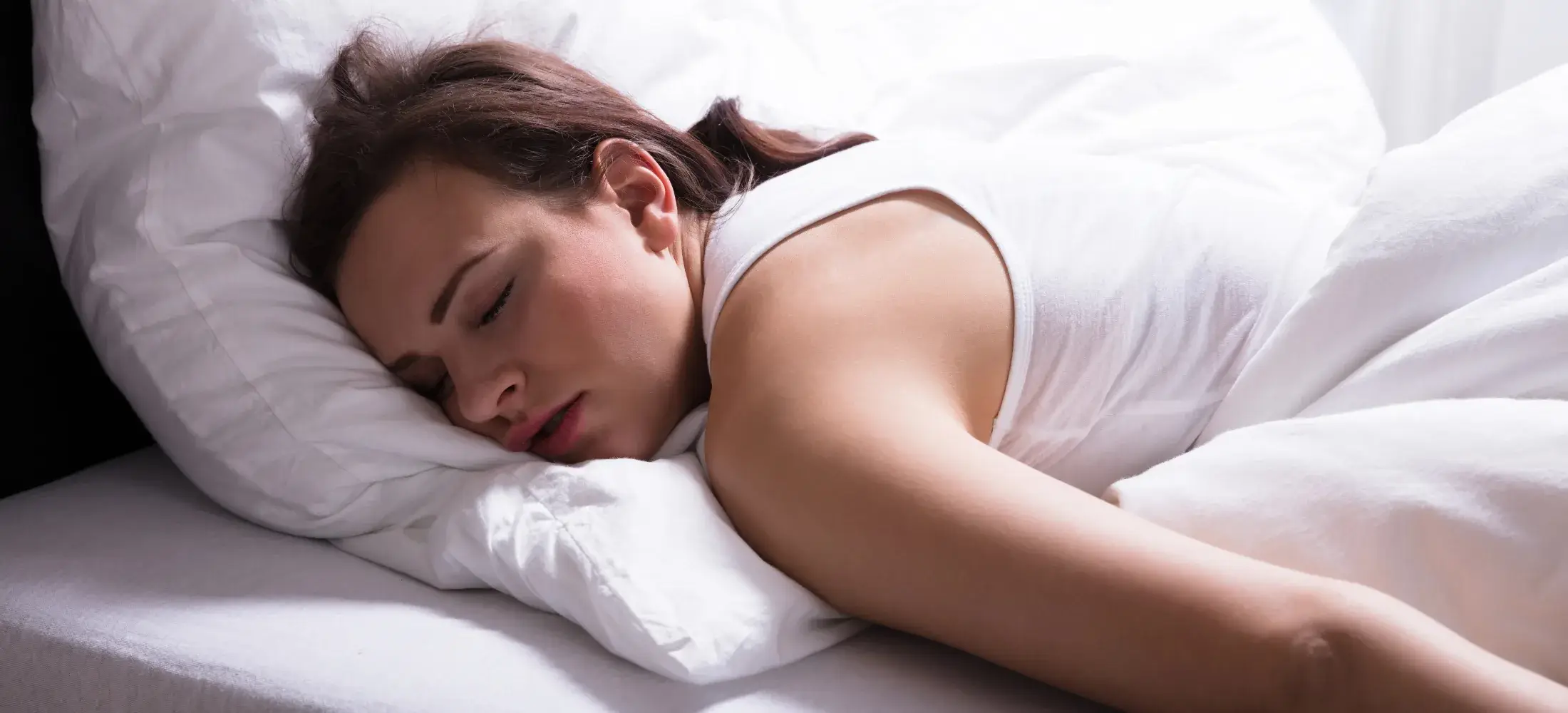 A woman asleep face down with her head turned to one side on the pillow