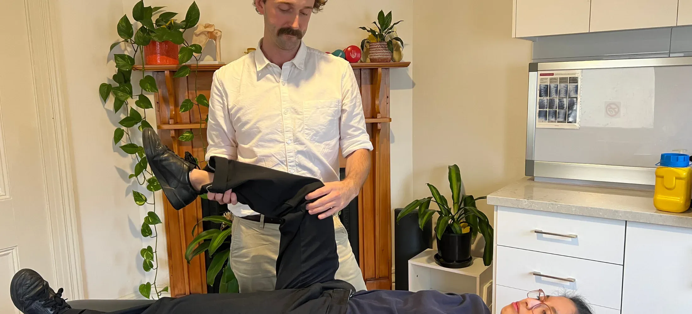 A practitioner raising a patient's leg to test hip and knee movement during an assessment