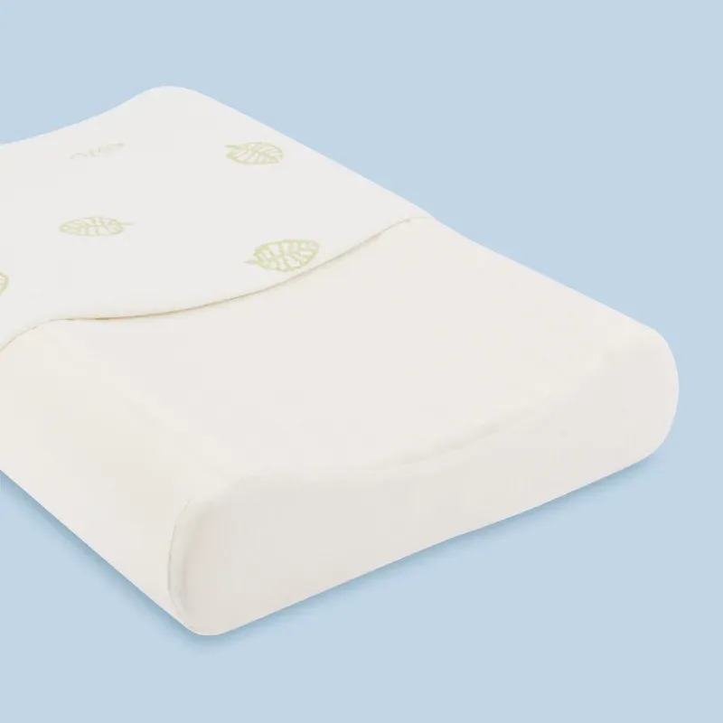 A contoured children's latex pillow with a cream leaf-patterned cover