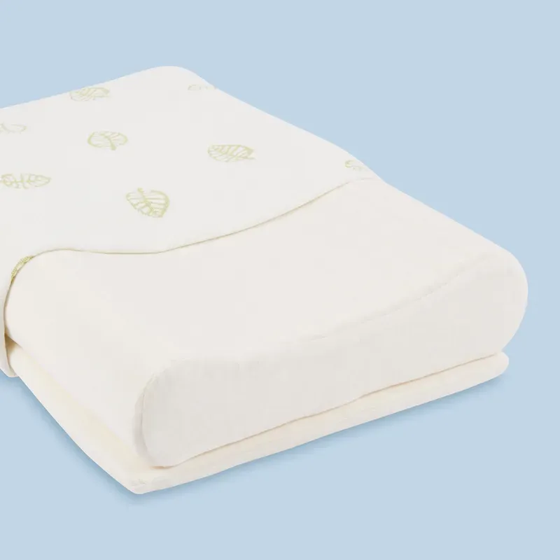 A contoured latex pillow, its leaf-patterned cover pulled halfway back to show the latex underneath