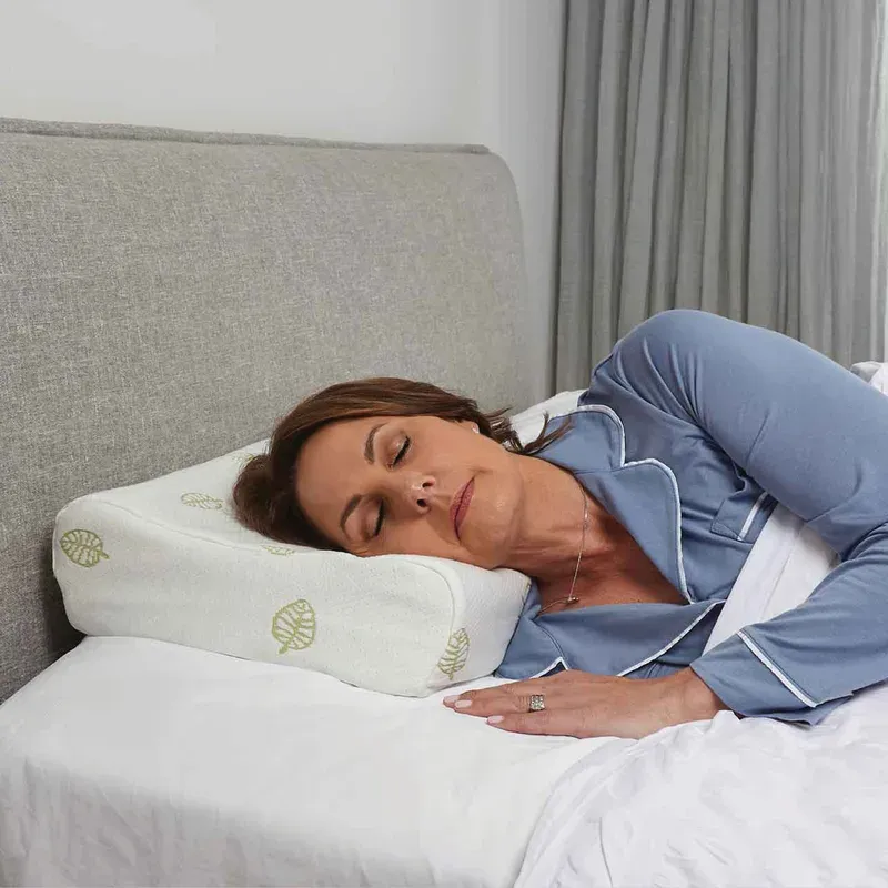 A woman asleep on her side, her neck in the pillow's lower contour