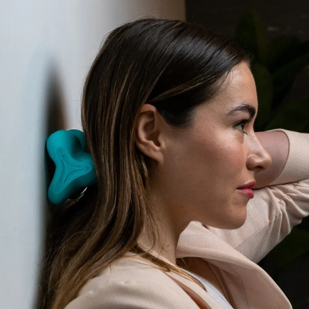 A woman leaning the back of her head against a wall with the device between her skull and the wall