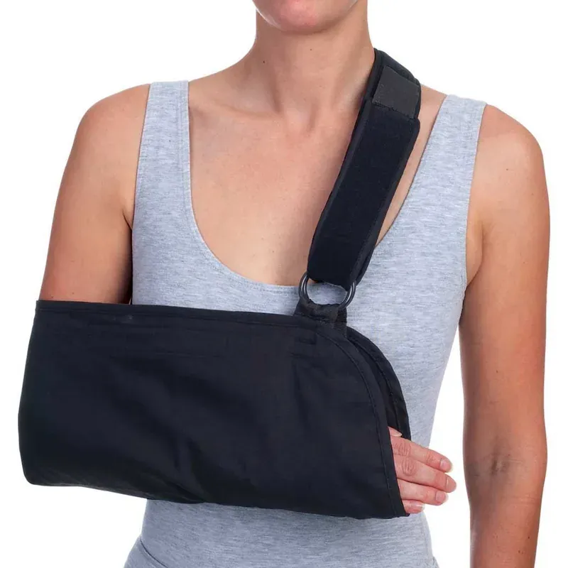 A black arm sling worn across the body, with a padded shoulder strap fastened through a D-ring