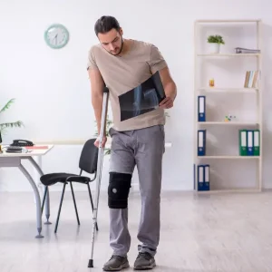 Patient with crutches and knee brace reviewing an X-ray during physiotherapy treatment and rehabilitation