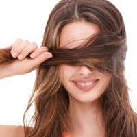 woman holding strands of brown hair, representing hair mineral and toxic element testing