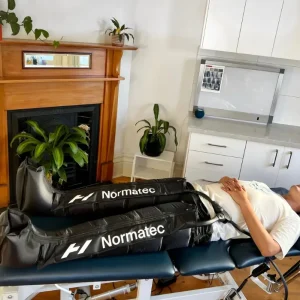 A physiotherapy clinic room in Melbourne with a treatment table and decompression Normatec boots for treating runners.