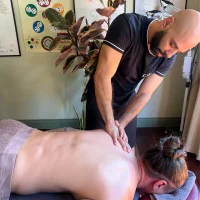 Expert Massage therapist performing a massage on a patient's upper back at Brunswick Health to relieve tightness and muscle soreness