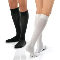 Two people standing back to back, one wearing black and the other wearing white knee-high compression socks, demonstrating the variety in medical-grade hosiery