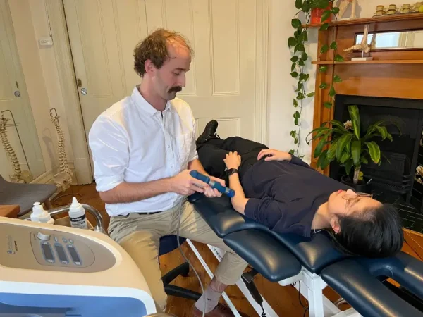 Physiotherapist Andrew Macdonald performing shock wave therapy on a patient's forearm.