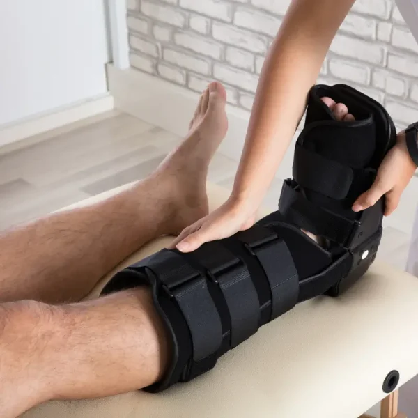 Physiotherapist fitting a CAM walker boot on a patient's leg to aid in recovery from an injury