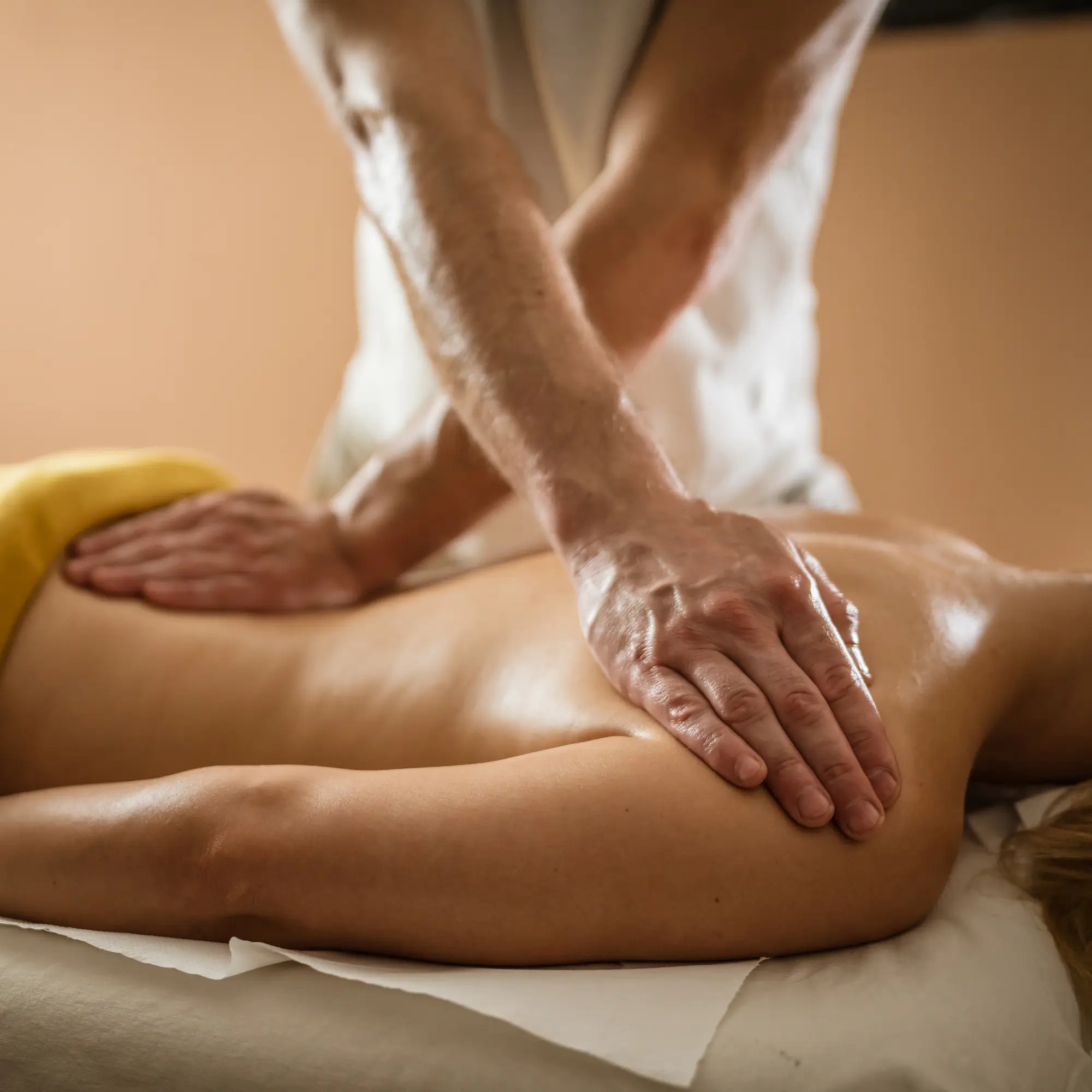 A close-up view of a therapeutic massage, focusing on a woman's back with a masseur applying pressure.