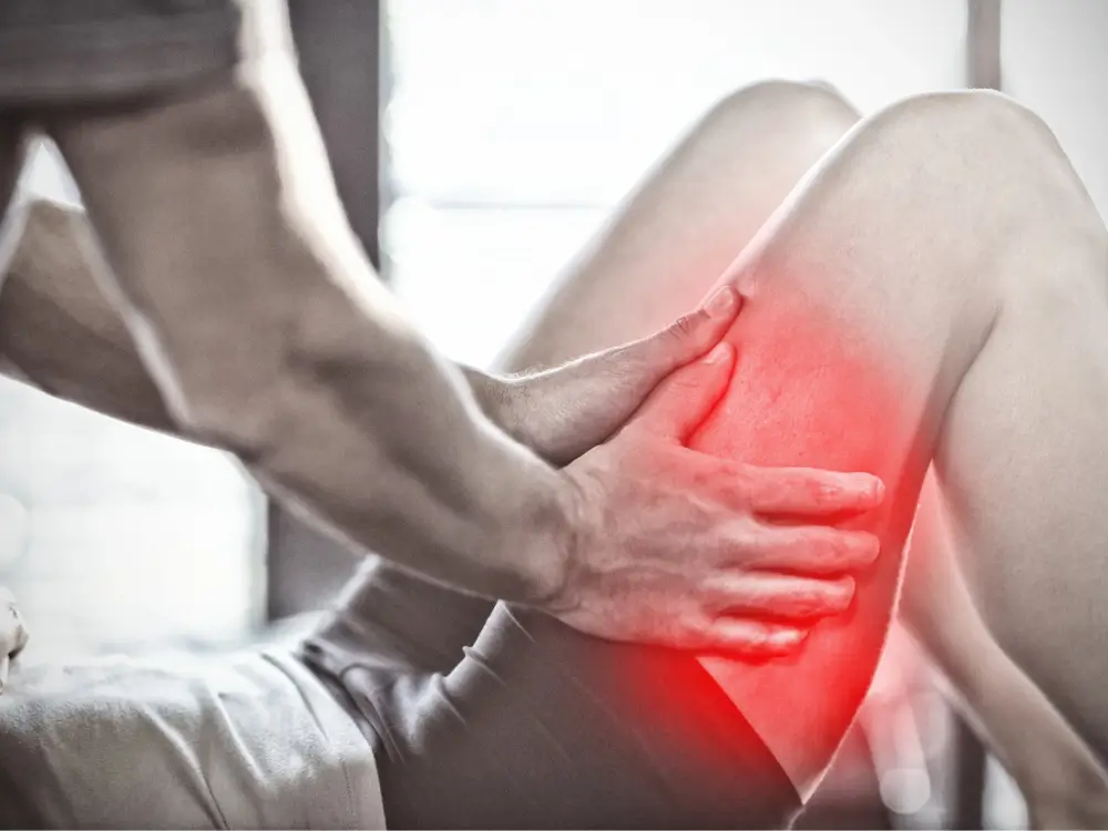 Physiotherapist massaging a patient's thigh with a red highlight, indicating iliotibial band (ITB) syndrome treatment
