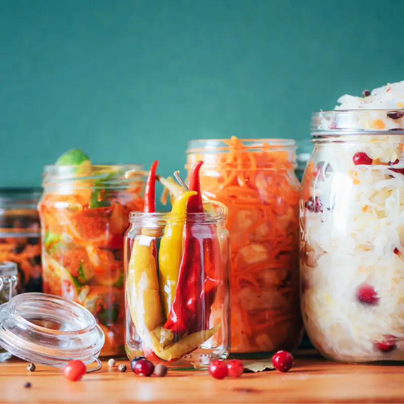 Jars of probiotic-rich fermented foods including peppers, carrots, and sauerkraut, supporting gut health