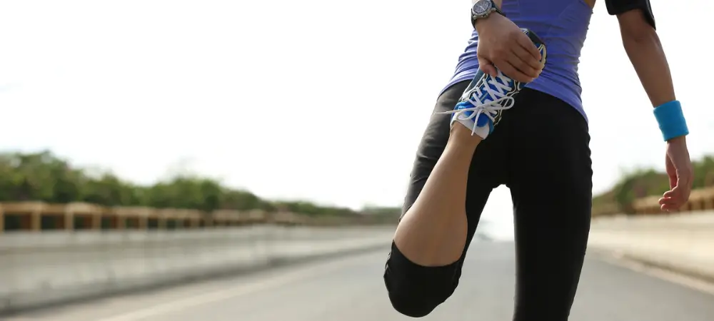 Runner performing a quad stretch to prevent knee pain and injury during training