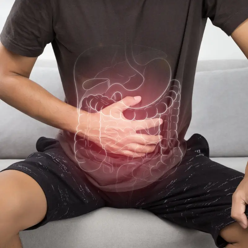 Man holding stomach with a highlighted digestive system, illustrating the benefits of probiotic colonic infusions for gut health and how probiotic colonic infusions can help IBS or diverticulitis and other digestive issues