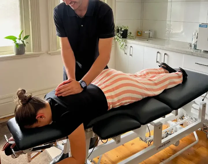 Brunswick Chiropractor performing a mid back adjustment on a patient lying on a treatment table in a well-lit clinic room