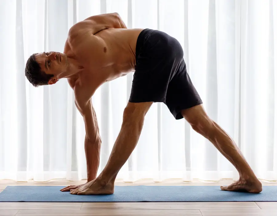 Man performing a low back stretch for sciatic nerve pain relief on a blue mat.