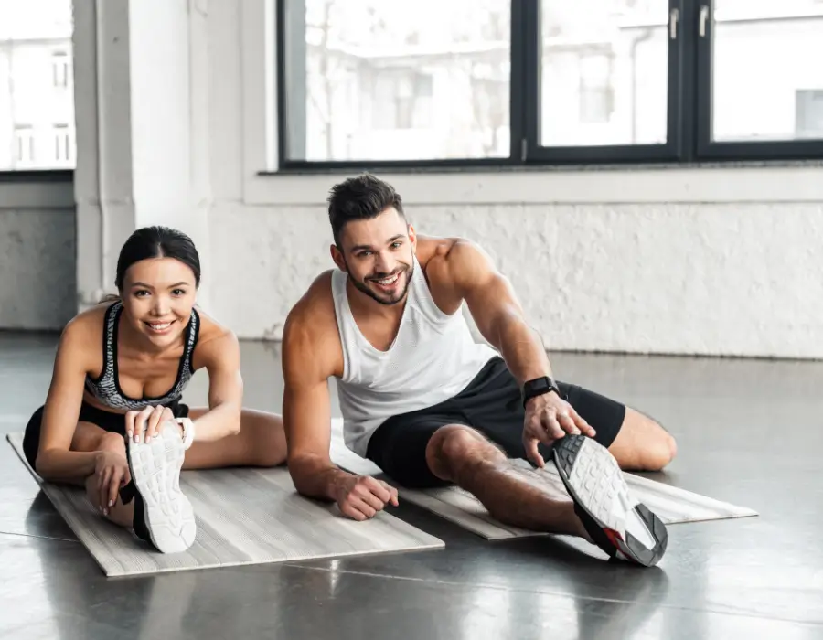 Man and woman stretching together on yoga mats for sciatica pain relief.