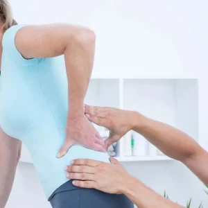 Physiotherapist assessing woman with chronic lower back pain