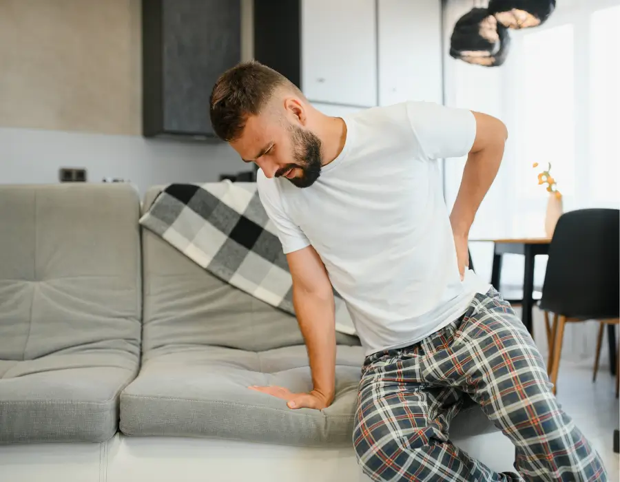 Man experiencing extreme low back pain and sciatica at home.