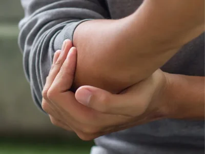 Close-up of a person holding their elbow due to tennis elbow pain.