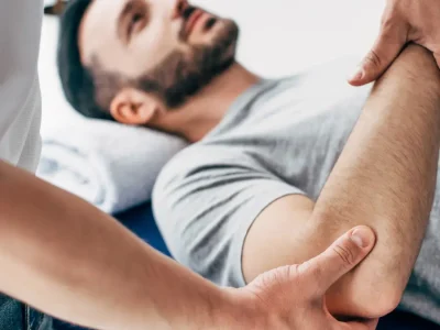 A physiotherapist treating a patient's tennis elbow with manual therapy.